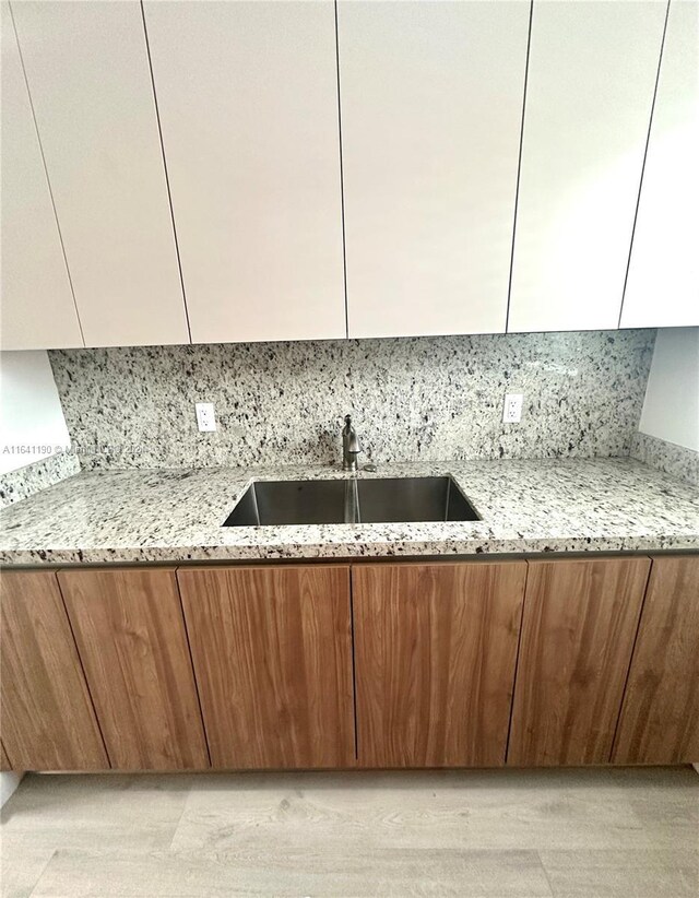 kitchen featuring backsplash, sink, and light stone countertops