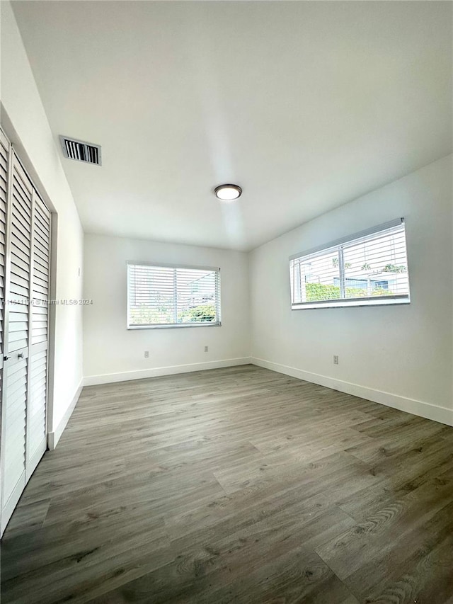 unfurnished bedroom featuring dark wood-type flooring and multiple windows