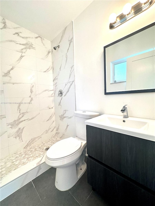 bathroom featuring tiled shower, toilet, vanity, and tile patterned flooring