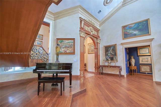 misc room featuring high vaulted ceiling, ornamental molding, and hardwood / wood-style flooring