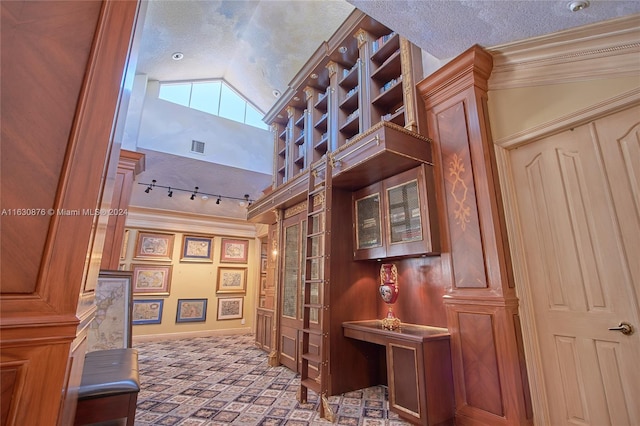 hallway featuring a textured ceiling, lofted ceiling, and rail lighting