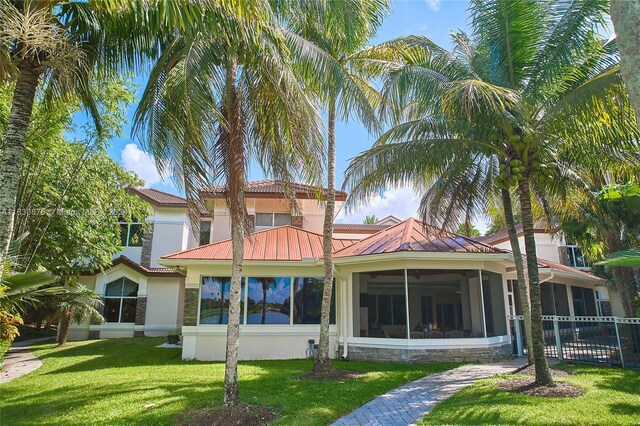 back of house featuring a lawn and a sunroom