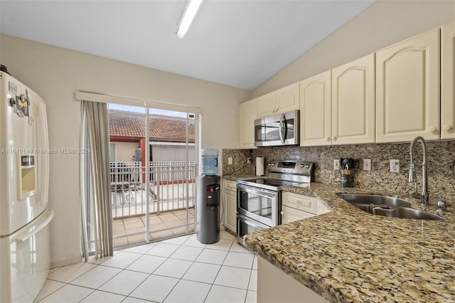 kitchen featuring appliances with stainless steel finishes, decorative backsplash, dark stone countertops, vaulted ceiling, and sink