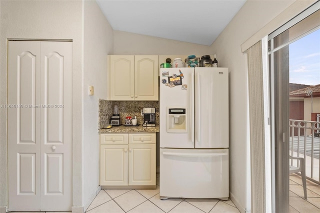 kitchen with light stone counters, white refrigerator with ice dispenser, tasteful backsplash, lofted ceiling, and light tile patterned floors