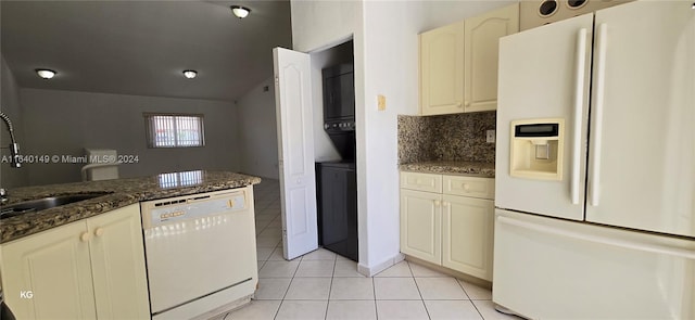 kitchen with sink, decorative backsplash, white appliances, light tile patterned floors, and dark stone countertops