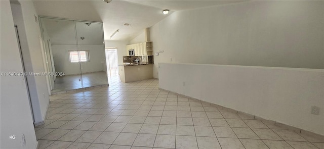 empty room featuring light tile patterned flooring and vaulted ceiling