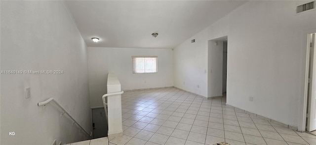 tiled empty room featuring vaulted ceiling