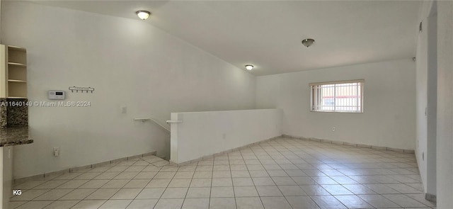 spare room with lofted ceiling and light tile patterned floors