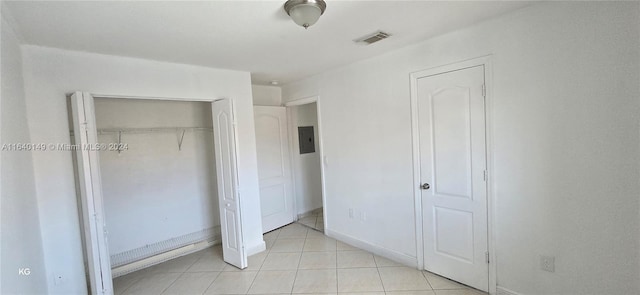 unfurnished bedroom with electric panel, a closet, and light tile patterned floors