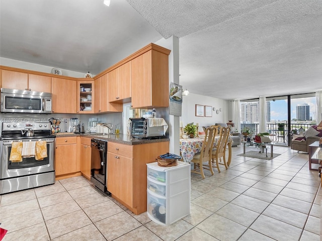 kitchen with a wall of windows, dishwasher, light tile patterned flooring, stove, and sink