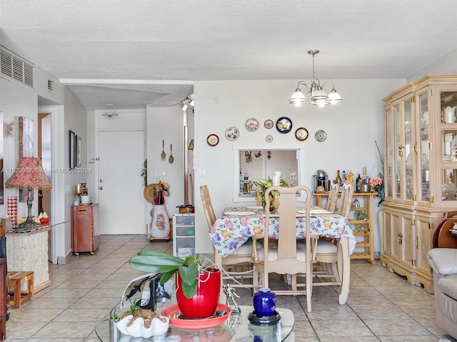 dining room featuring a notable chandelier, a textured ceiling, and light tile patterned floors