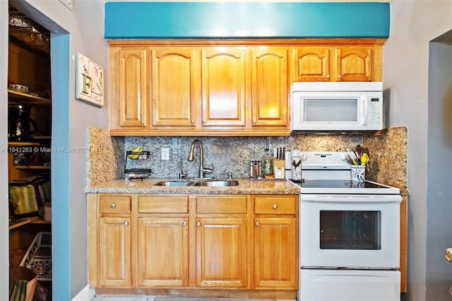 kitchen with tasteful backsplash, white appliances, a sink, and light stone countertops