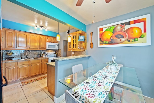 kitchen with light tile patterned floors, white appliances, a sink, decorative backsplash, and brown cabinetry