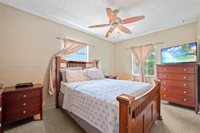 bedroom with light carpet, multiple windows, and a textured ceiling