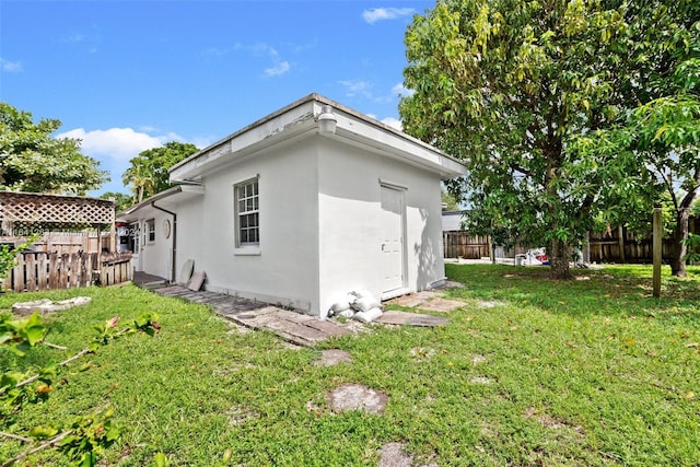 view of side of home featuring fence private yard, a lawn, and stucco siding