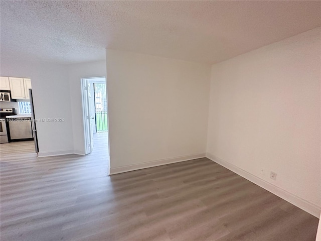 unfurnished room with wood-type flooring and a textured ceiling