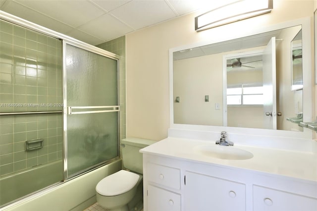 full bathroom with toilet, vanity, tile patterned floors, enclosed tub / shower combo, and ceiling fan