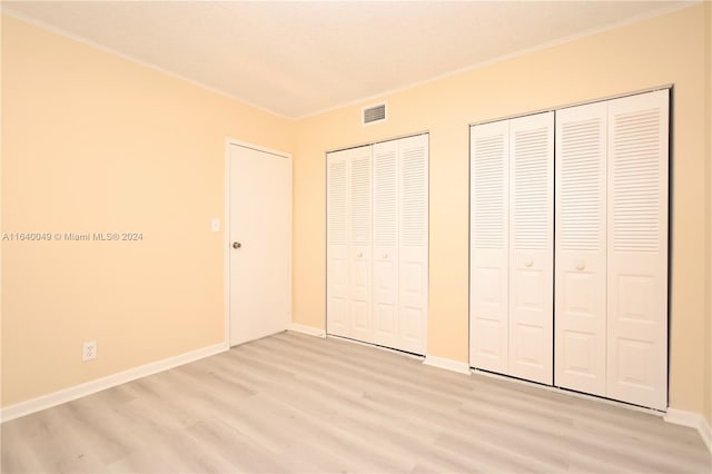 unfurnished bedroom featuring light wood-type flooring and two closets