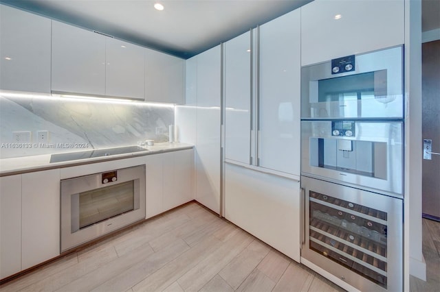 kitchen featuring decorative backsplash, white cabinetry, wine cooler, and oven