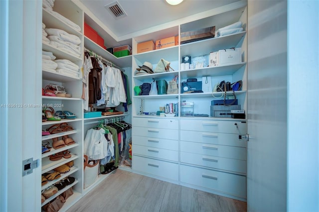 walk in closet with light hardwood / wood-style floors