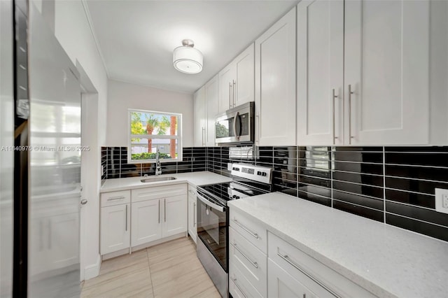 kitchen with backsplash, stainless steel appliances, sink, light tile patterned floors, and white cabinetry