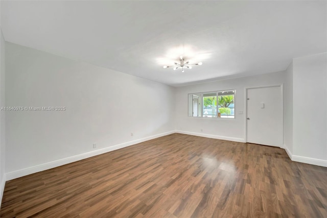 unfurnished room featuring dark hardwood / wood-style flooring and a notable chandelier