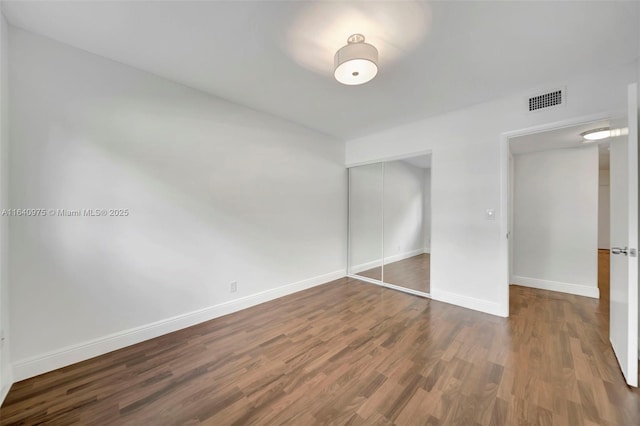 unfurnished bedroom featuring dark wood-type flooring and a closet