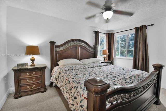 bedroom featuring a textured ceiling, light colored carpet, and ceiling fan