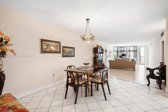 tiled dining area with a notable chandelier and a textured ceiling