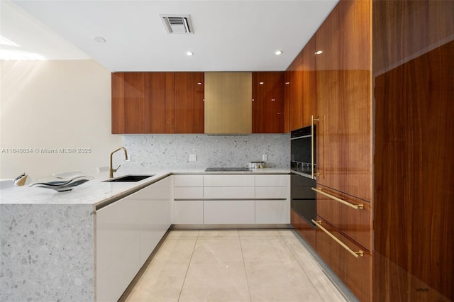 kitchen featuring modern cabinets, a sink, visible vents, and wall oven