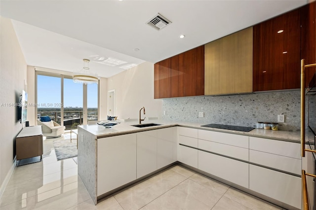 kitchen featuring tasteful backsplash, black electric cooktop, a sink, and light countertops