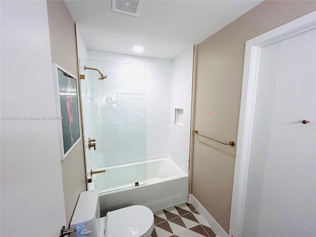 bathroom with toilet, tiled shower / bath combo, and tile patterned flooring