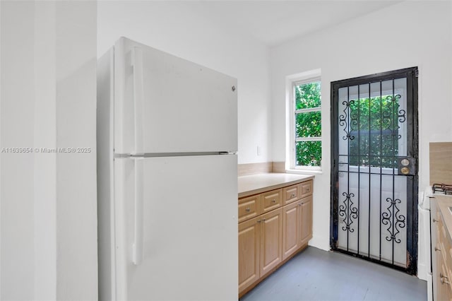 kitchen with light brown cabinetry and white fridge