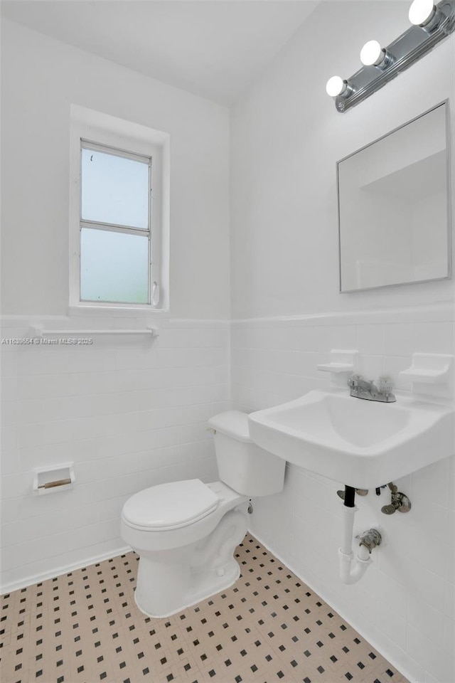 bathroom featuring tile walls, sink, and toilet