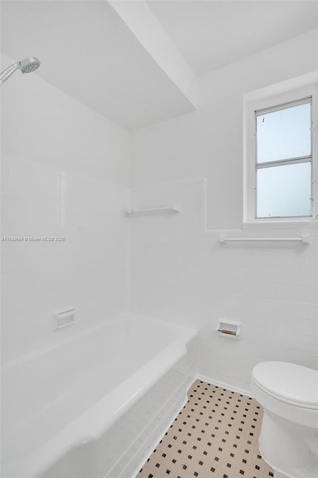 bathroom with bathtub / shower combination, tile walls, and toilet