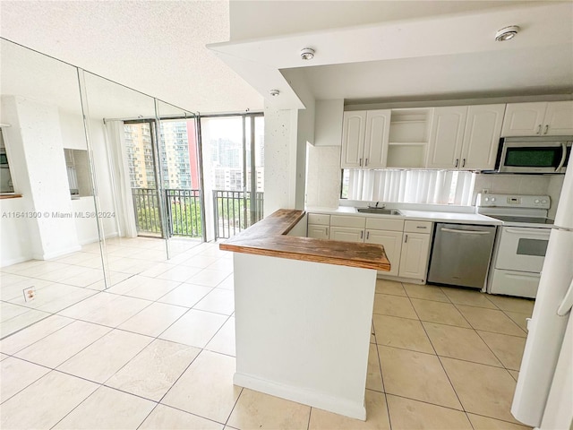 kitchen with appliances with stainless steel finishes, sink, light tile patterned flooring, floor to ceiling windows, and kitchen peninsula