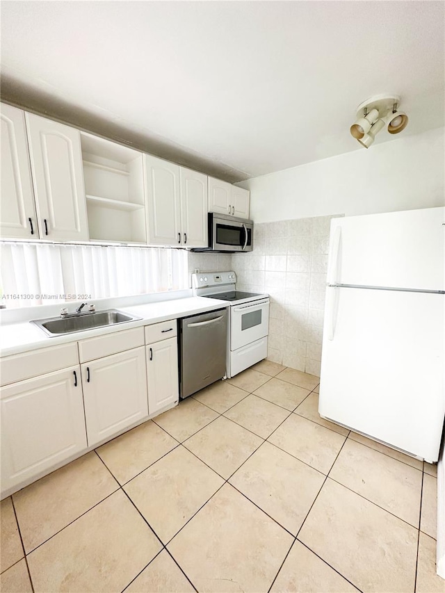 kitchen with light tile patterned flooring, white cabinets, stainless steel appliances, and sink