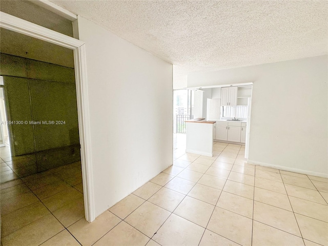 empty room with light tile patterned floors, sink, and a textured ceiling