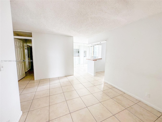 unfurnished room featuring a textured ceiling and light tile patterned floors