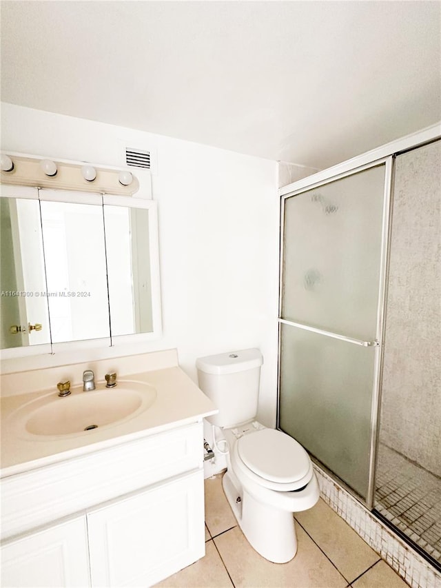 bathroom featuring vanity, toilet, tile patterned flooring, and an enclosed shower