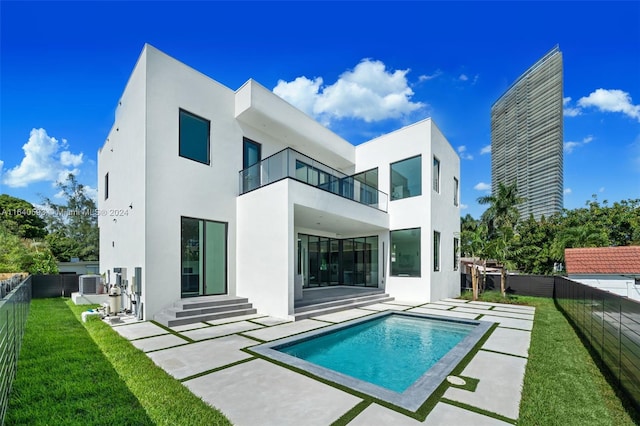 rear view of house featuring a fenced in pool, a yard, a patio, central AC unit, and a balcony