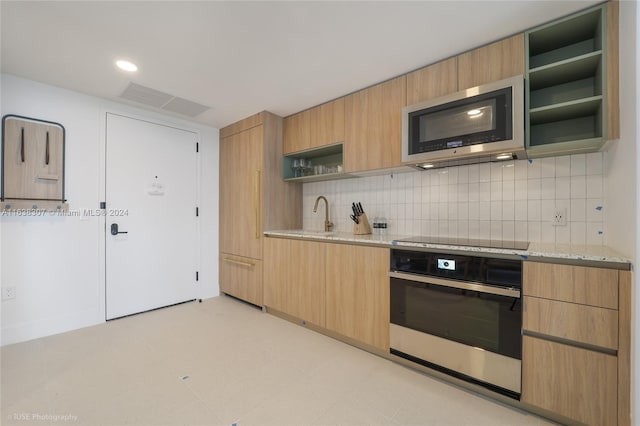 kitchen with decorative backsplash, light brown cabinets, light stone counters, light tile patterned floors, and stainless steel appliances