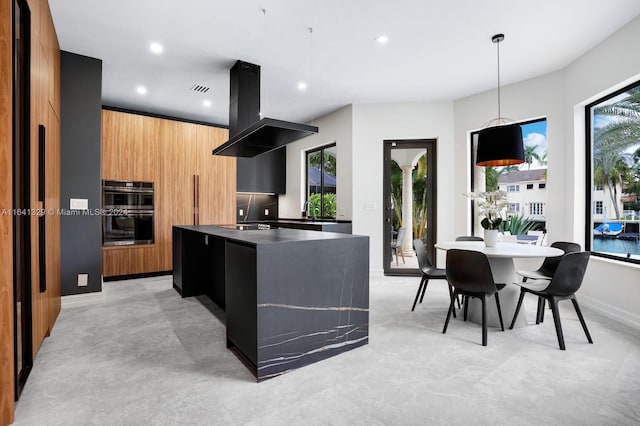 kitchen featuring sink, black double oven, decorative light fixtures, island range hood, and a kitchen island