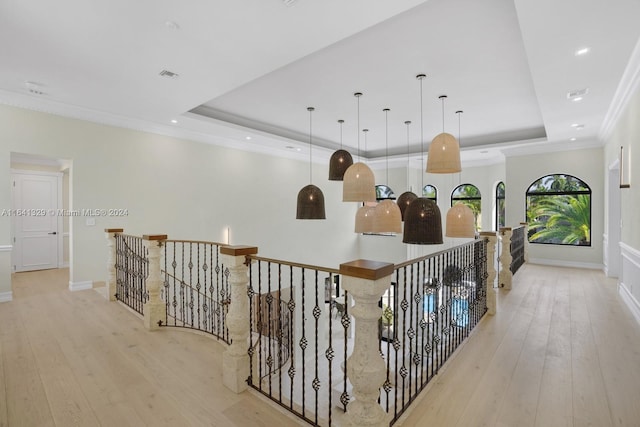 hall with a tray ceiling, crown molding, and light hardwood / wood-style floors