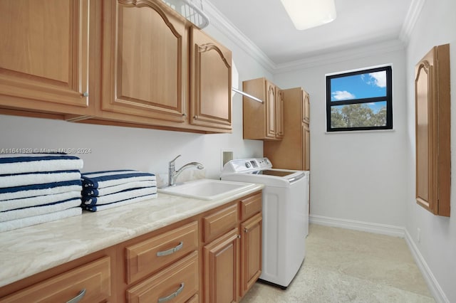 clothes washing area featuring crown molding, washer and dryer, cabinets, and sink