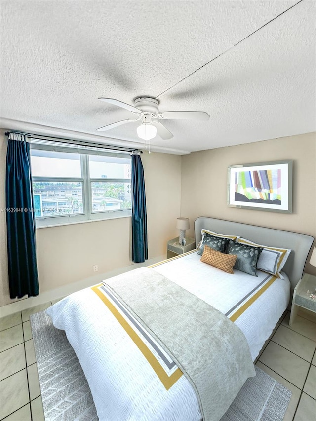 tiled bedroom with ceiling fan and a textured ceiling