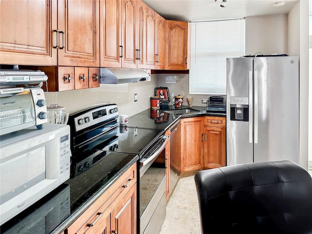 kitchen featuring light tile patterned floors, sink, stainless steel appliances, and dark stone countertops