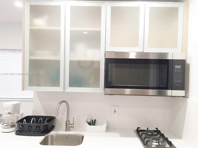 room details featuring white cabinets, gas cooktop, and sink