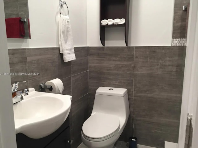 bathroom with tile walls, toilet, and vanity