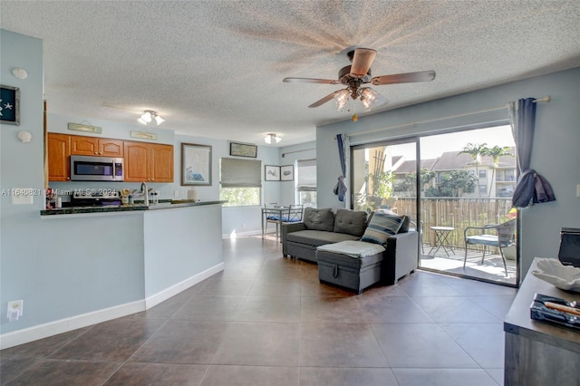 tiled living room with ceiling fan and a textured ceiling